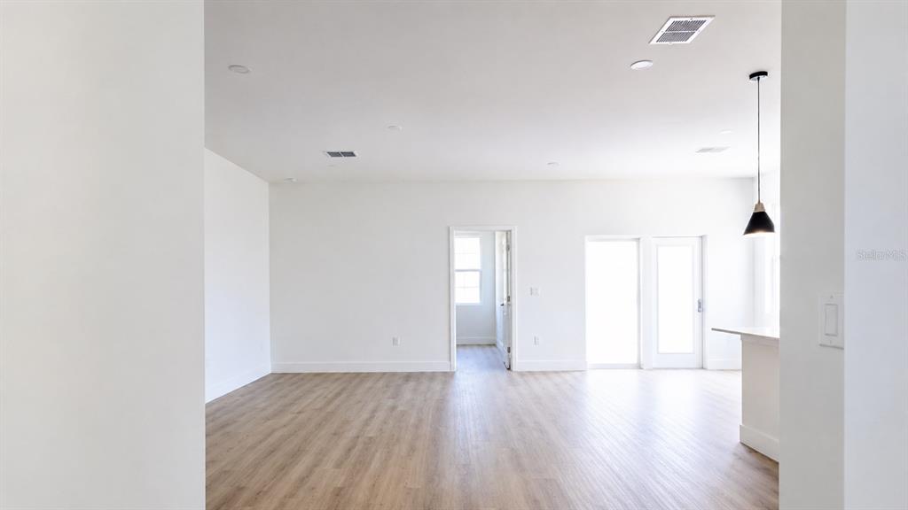 An open-concept living area features white walls, light wood-look flooring, and a kitchen island — 980 TAHITI AVENUE SE, PALM BAY, FL