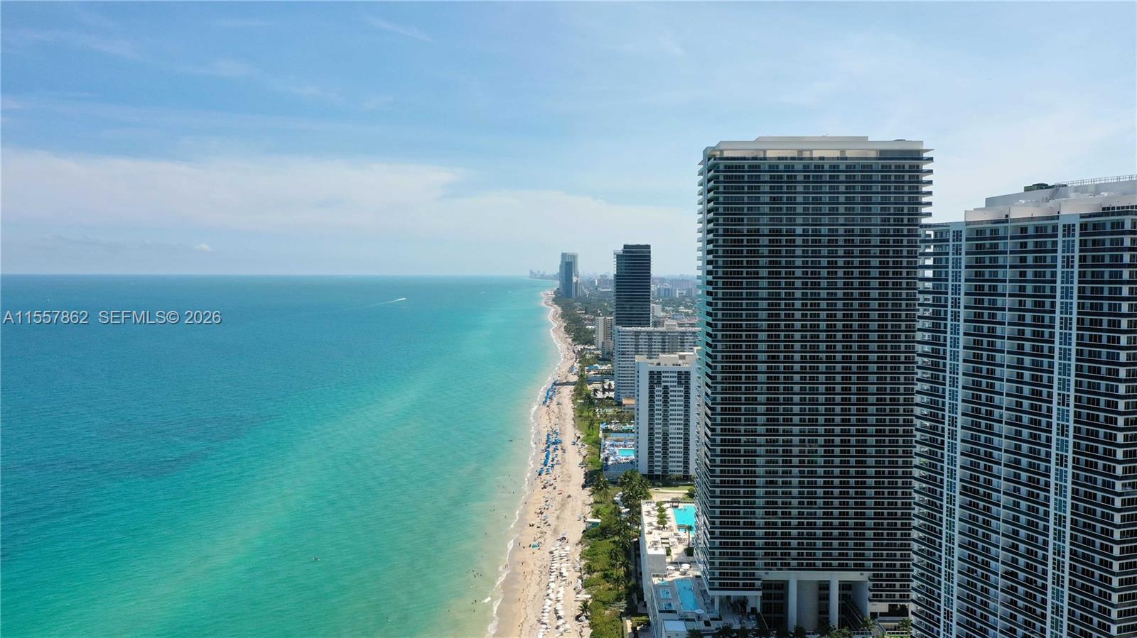 An aerial view shows high-rise residential buildings along a sandy beach and the ocean — 4111 S Ocean Dr # 2111, Hollywood FL 33019, HOLLYWOOD, FL