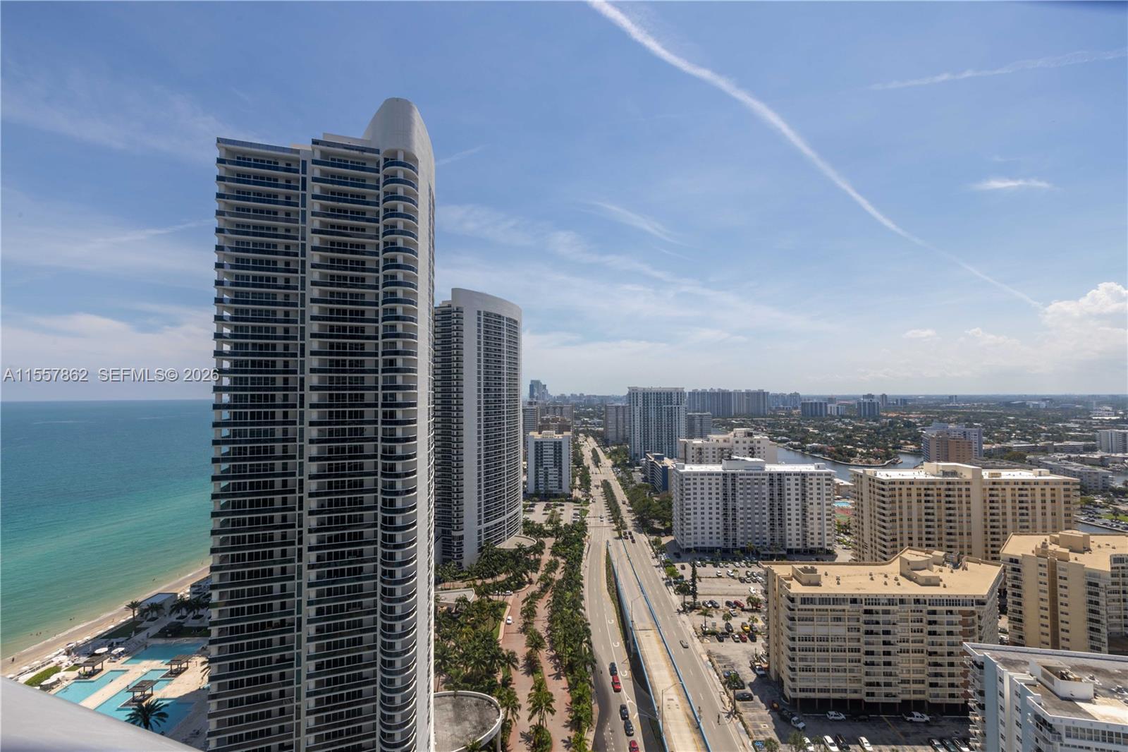 An aerial view shows high-rise residential towers along a coastline next to a highway — 4111 S Ocean Dr # 2111, Hollywood FL 33019, HOLLYWOOD, FL