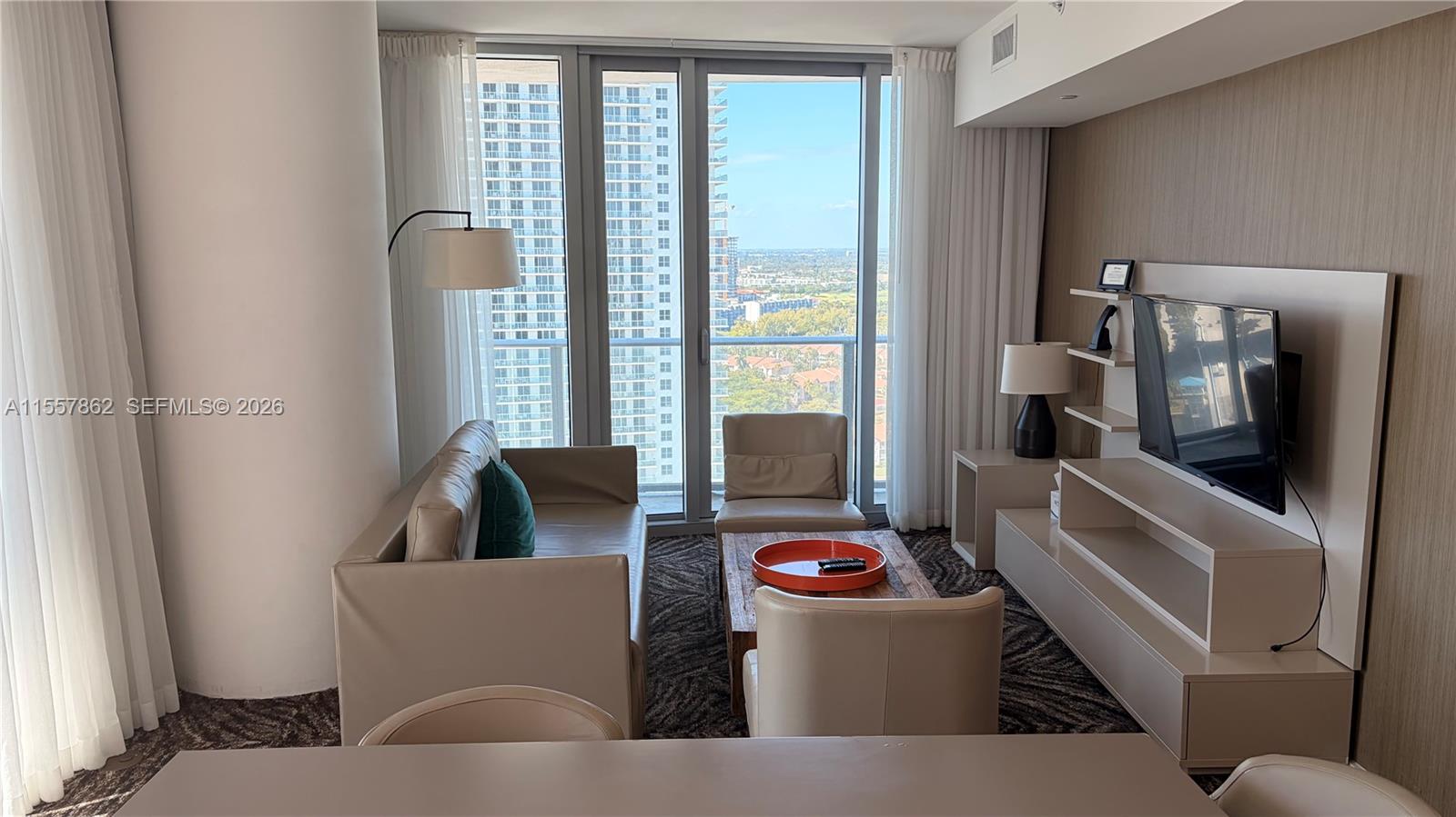 A modern living room features a beige sofa, two armchairs, and a wall-mounted television — 4111 S Ocean Dr # 2111, Hollywood FL 33019, HOLLYWOOD, FL