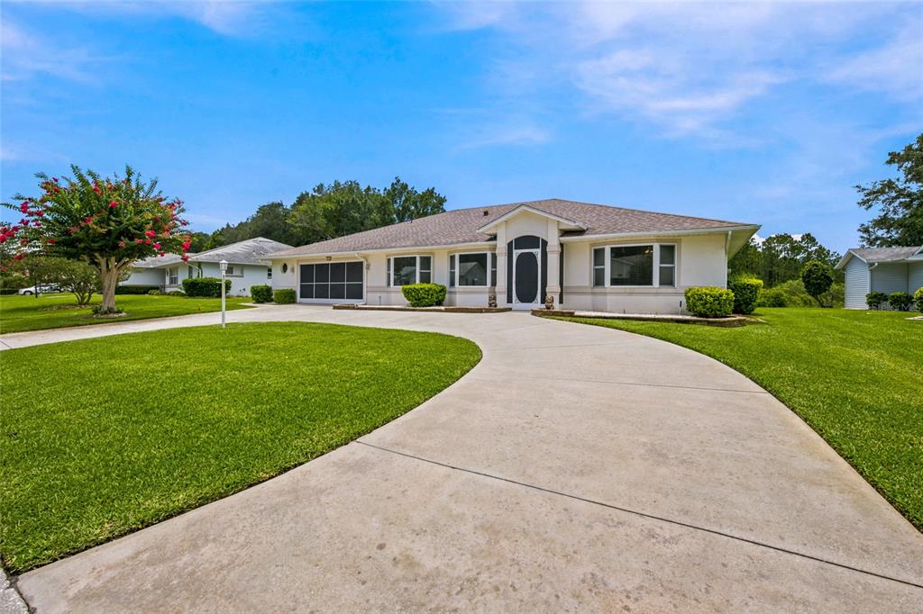A single-story house with a concrete driveway, a two-car garage, and a manicured lawn — 27202 RACQUET CIRCLE, LEESBURG, FL
