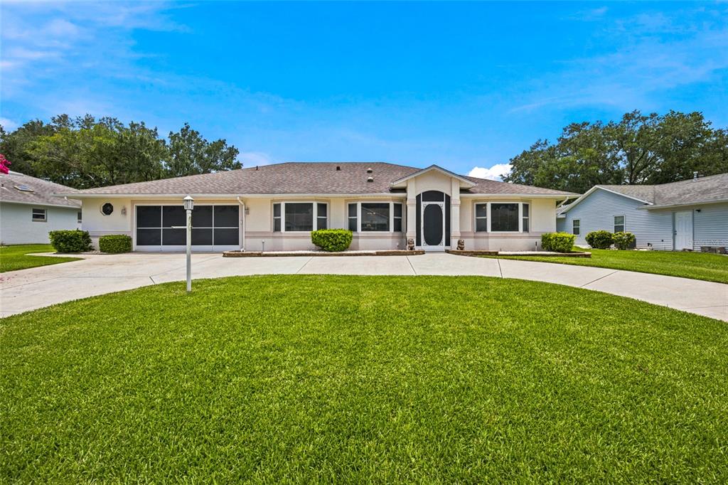 A single-story house with a circular driveway, a two-car garage, and a central arched entryway — 27202 RACQUET CIRCLE, LEESBURG, FL