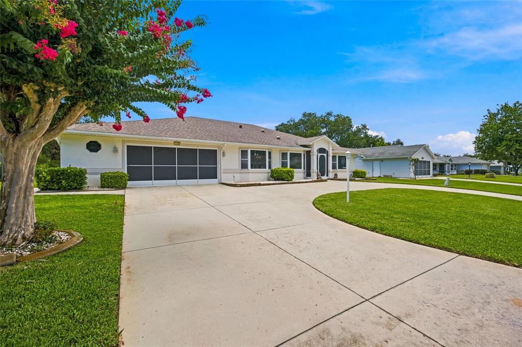 A single-story house with a white exterior, a screened garage, and a concrete driveway — 27202 RACQUET CIRCLE, LEESBURG, FL