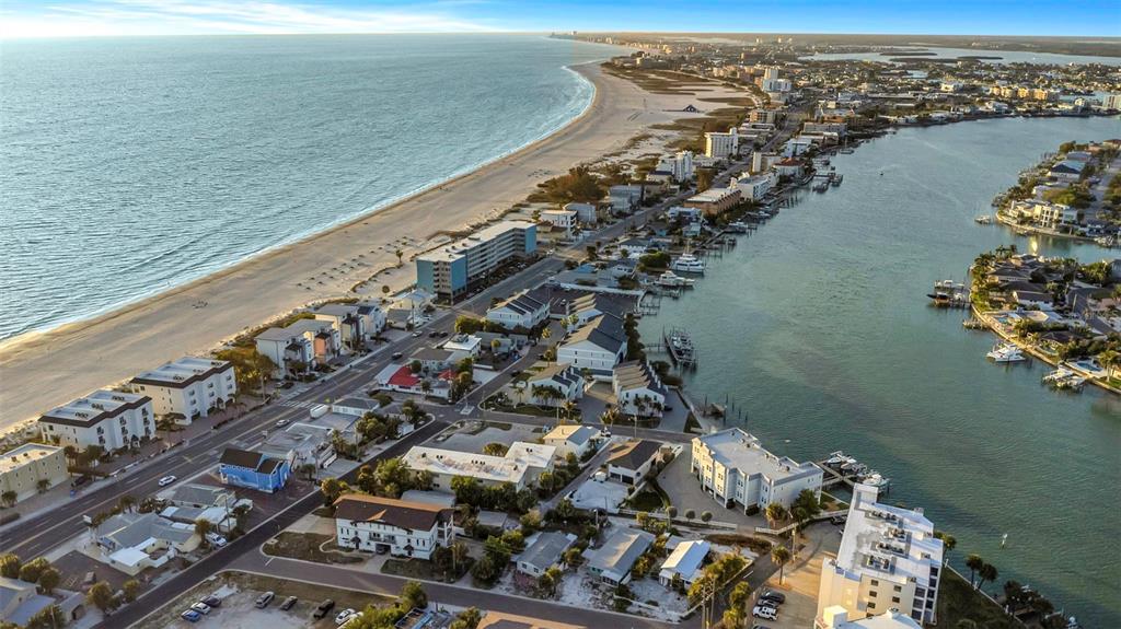 An aerial view shows a coastal neighborhood with a green arrow pointing to a house — 148 98TH AVENUE, TREASURE ISLAND, FL