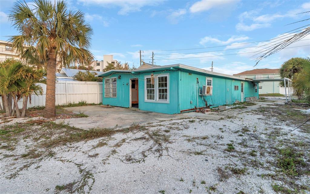 An aerial view shows a rectangular house with a shingled roof surrounded by sandy landscaping — 148 98TH AVENUE, TREASURE ISLAND, FL
