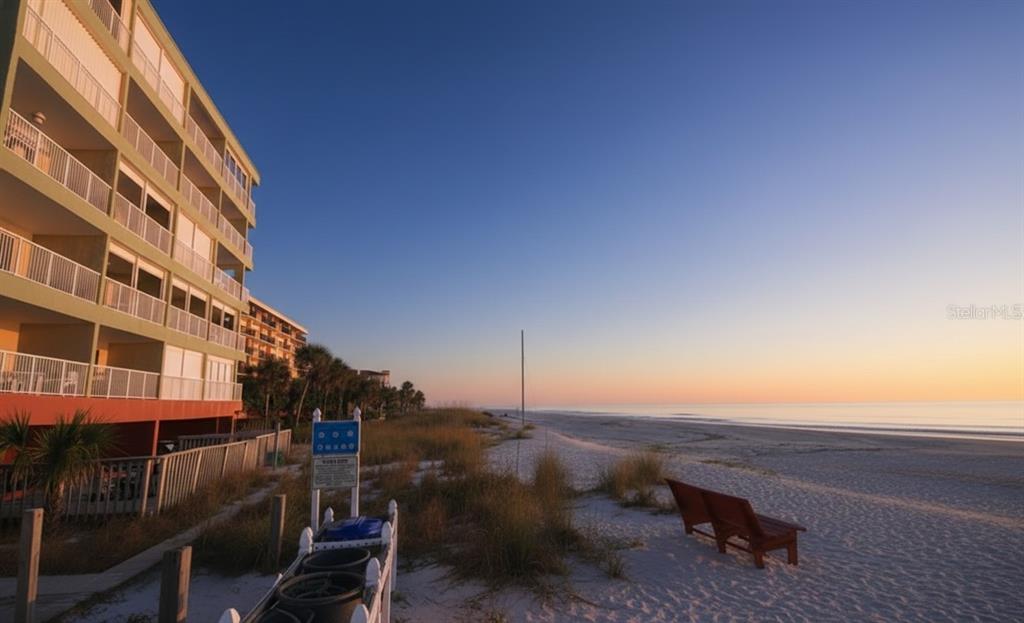 A multi-story beachfront condo building stands next to a sandy beach at sunrise — 19236 GULF BOULEVARD UNIT 104, INDIAN SHORES, FL