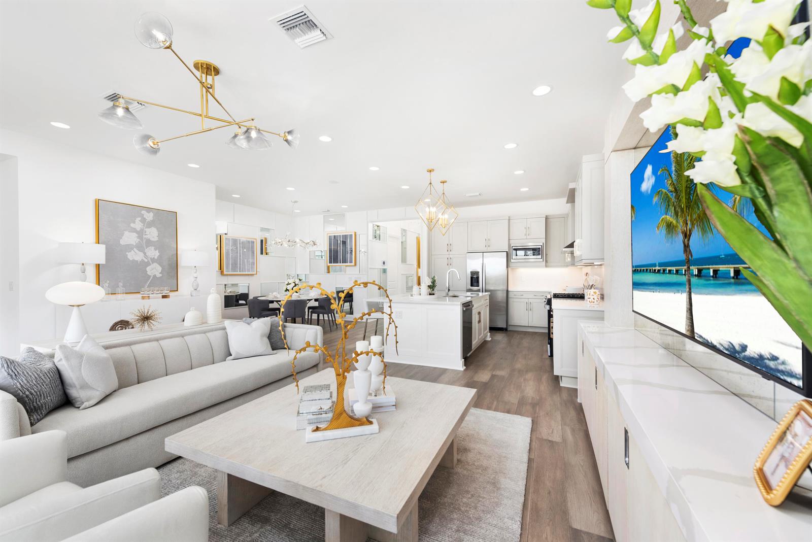 A modern open-concept living room and kitchen featuring white cabinetry, light wood flooring, and gold accents — 481 40th Street, West Palm Beach FL 33407, WEST PALM BEACH, FL