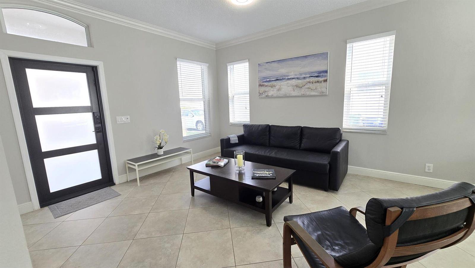 A living room features a black sofa, a coffee table, and a modern front door — 6878 NW 33rd Street, Margate FL 33063, MARGATE, FL