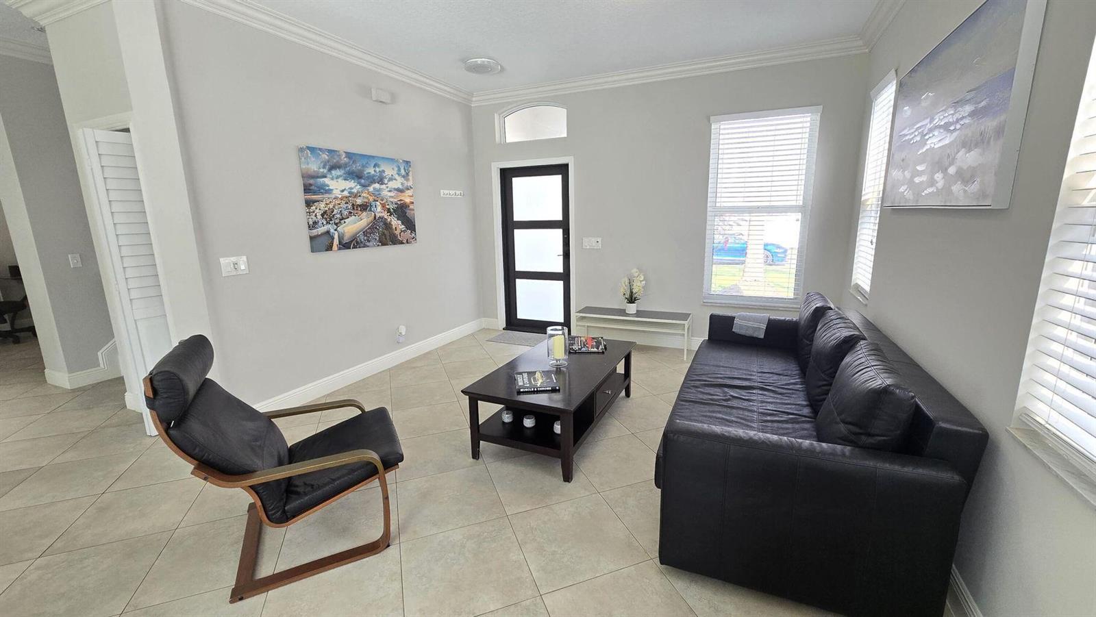 A living room features light tile floors, a black sofa, a matching armchair, and a coffee table — 6878 NW 33rd Street, Margate FL 33063, MARGATE, FL
