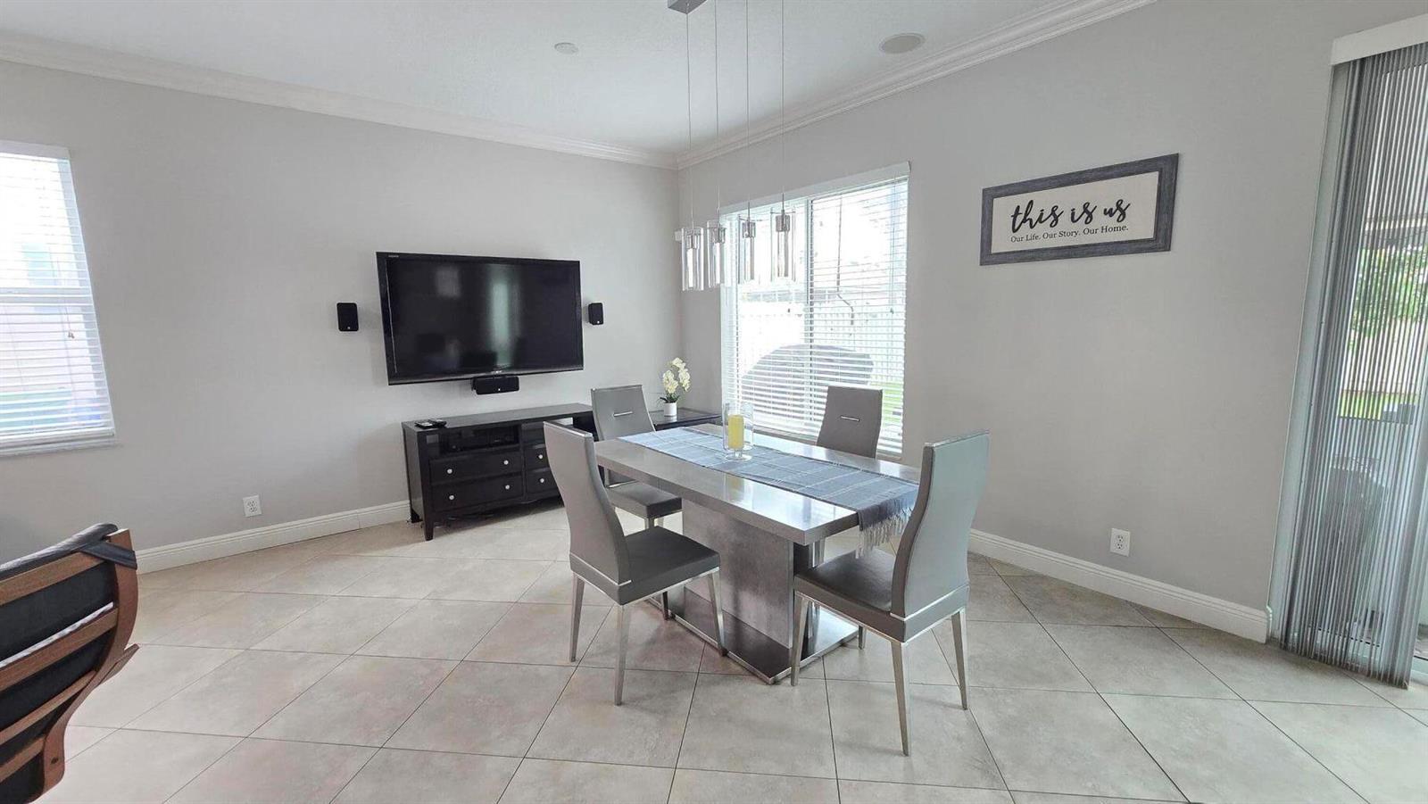 A dining area features a modern table with four chairs, a television, and light-colored tile — 6878 NW 33rd Street, Margate FL 33063, MARGATE, FL