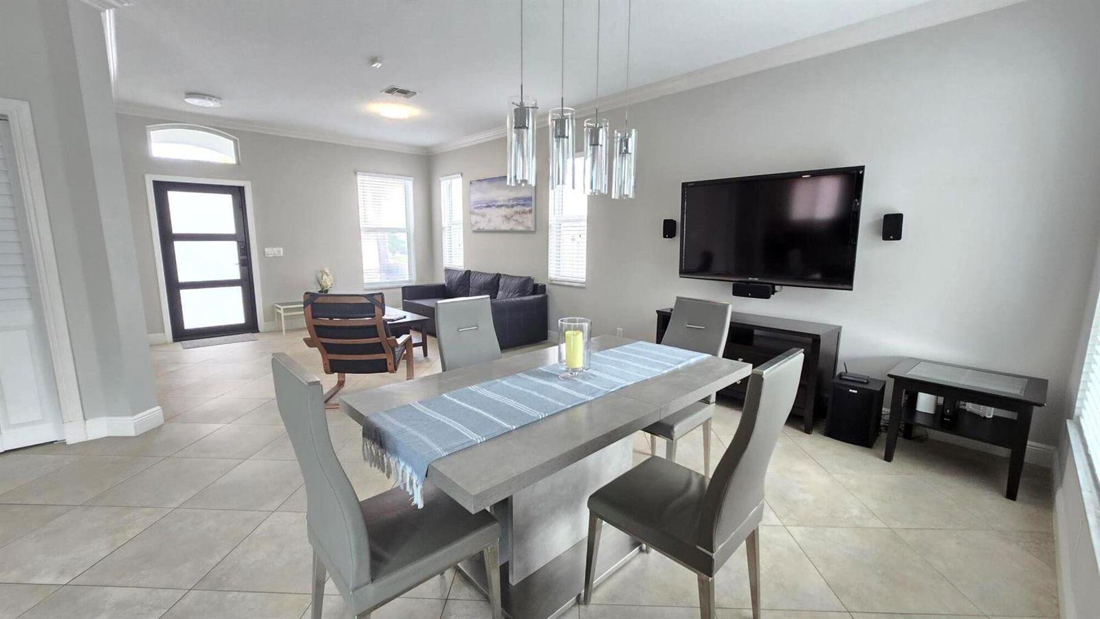 A dining area with a gray table and chairs sits in front of a living room — 6878 NW 33rd Street, Margate FL 33063, MARGATE, FL