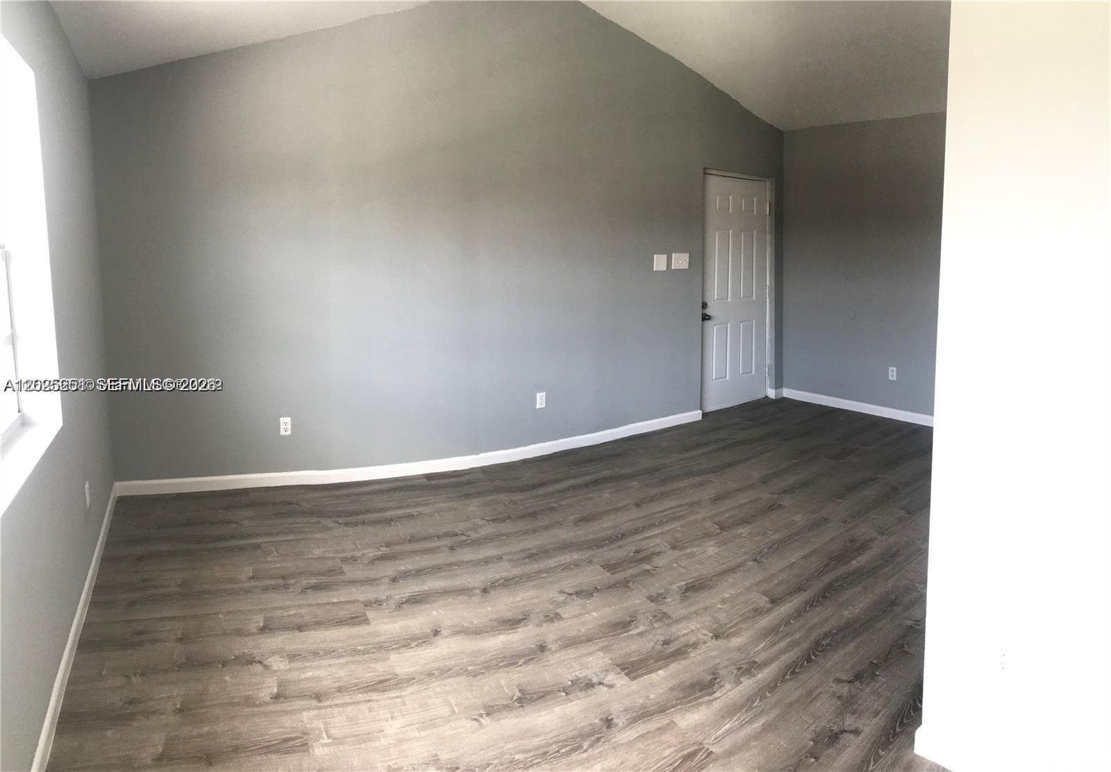 An empty room features gray walls, vaulted ceilings, and wood-look laminate flooring — 15285 SW 107th Ln # 206, Miami FL 33196, MIAMI, FL