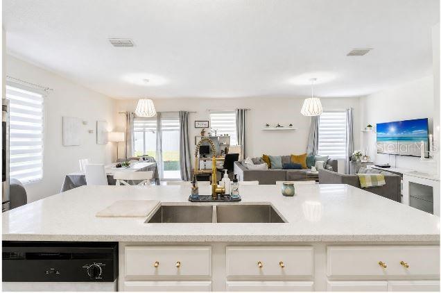 A kitchen island with a double sink overlooks an open-concept living and dining area — 6103 GREY HERON DRIVE, WINTER HAVEN, FL
