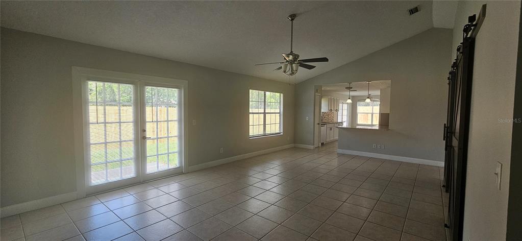 A living room with tile floors, a vaulted ceiling, a ceiling fan, and French doors — 2625 SPRING VALLEY CIRCLE, DELAND, FL