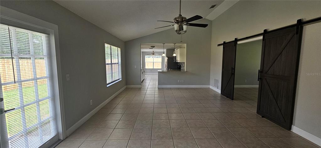 A tiled living area features a vaulted ceiling, sliding barn doors, and a kitchen pass-through — 2625 SPRING VALLEY CIRCLE, DELAND, FL
