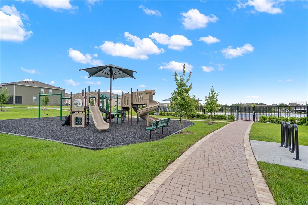 A playground with slides and a swing set sits next to a paved walkway — 1530 PLANK PLACE, DAVENPORT, FL