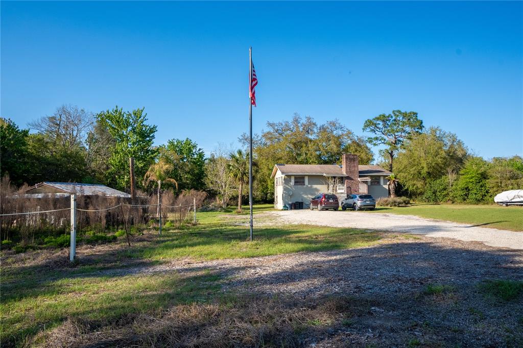 A single-story house with a brick chimney sits on a large lot with a flagpole — 2468 FAWN RUN, OVIEDO, FL