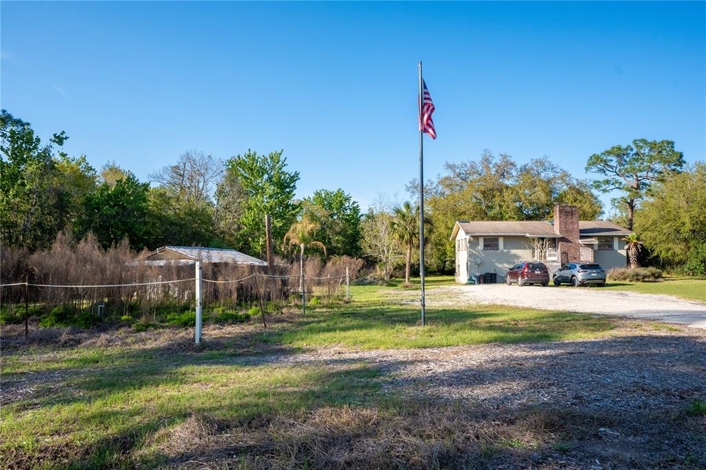 A house with a gravel driveway and a flagpole stands on a grassy lot — 2468 FAWN RUN, OVIEDO, FL