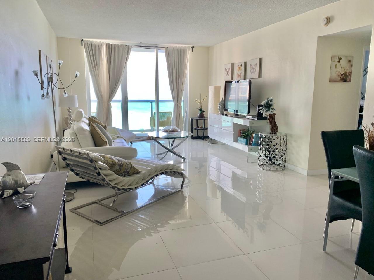A bright living room features white tile floors, a lounge chair, and ocean views — 3901 S Ocean Dr # 10Z, Hollywood FL 33019, HOLLYWOOD, FL