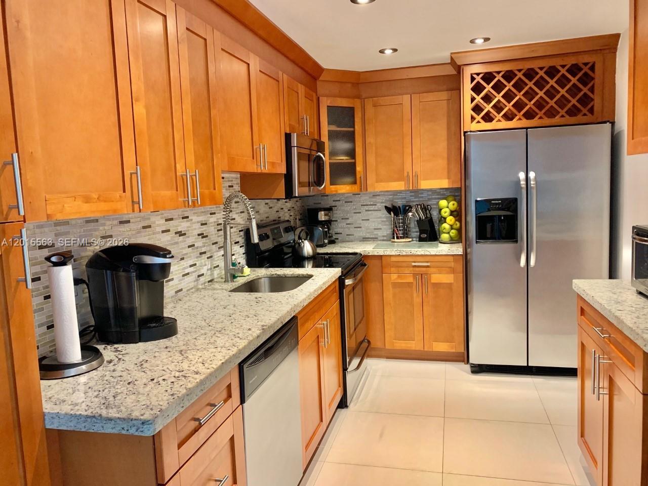 A kitchen features wood cabinets, granite countertops, stainless steel appliances, and a tiled backsplash — 3901 S Ocean Dr # 10Z, Hollywood FL 33019, HOLLYWOOD, FL