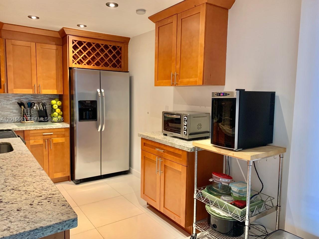 A kitchen features wood cabinets, granite countertops, stainless steel appliances, and a metal storage cart — 3901 S Ocean Dr # 10Z, Hollywood FL 33019, HOLLYWOOD, FL