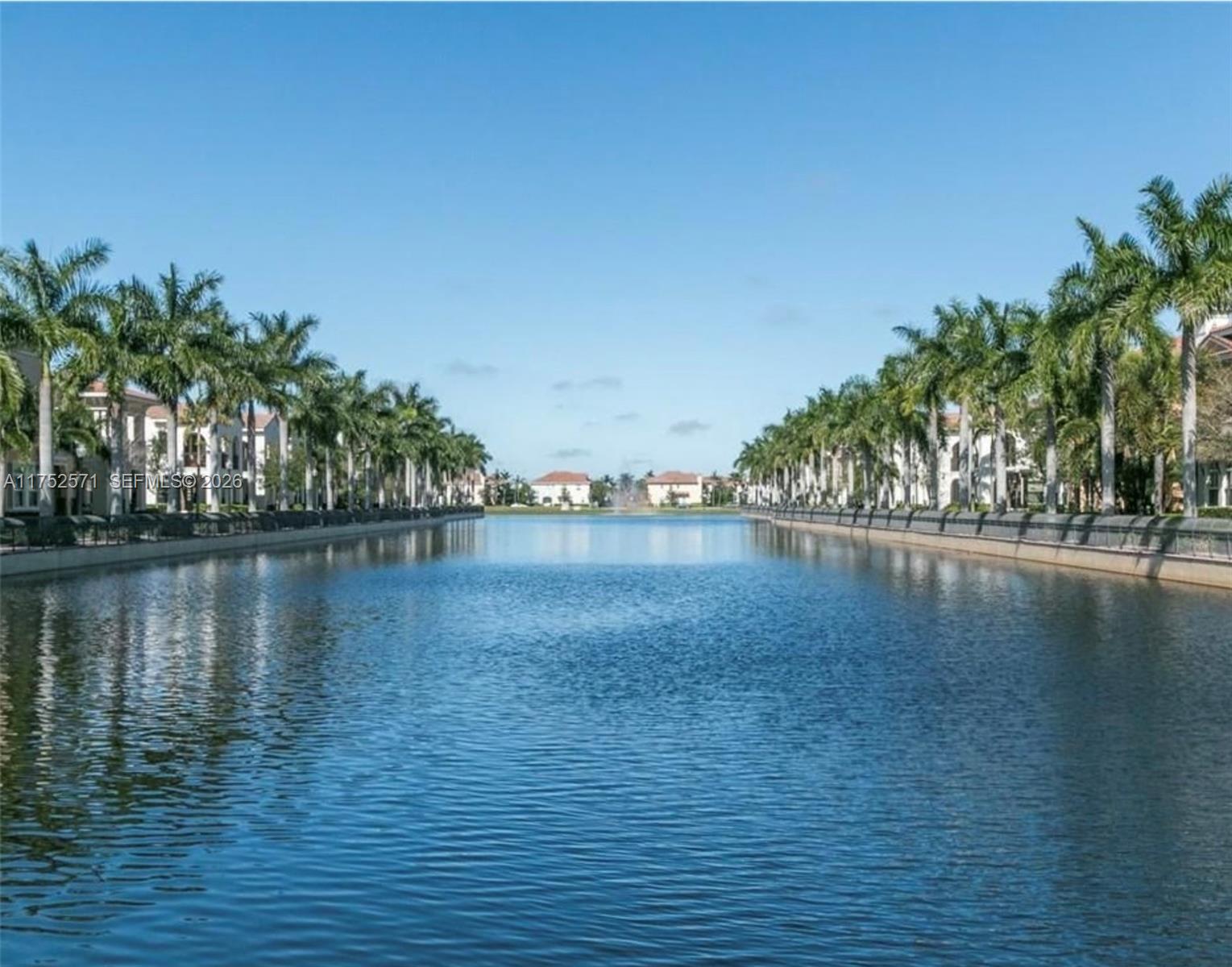 A canal runs between two rows of palm trees and residential buildings under a clear sky — 2910 NW 124th Way # 2910, Sunrise FL 33323, SUNRISE, FL