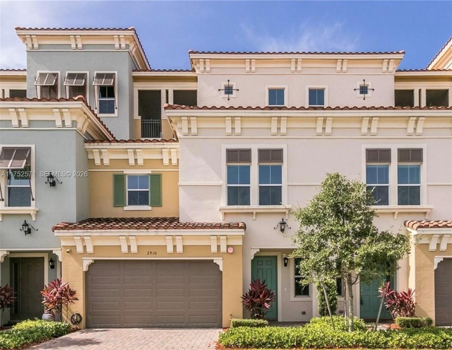 A multi-story townhouse exterior features a two-car garage, stucco walls, and a tiled roof — 2910 NW 124th Way # 2910, Sunrise FL 33323, SUNRISE, FL