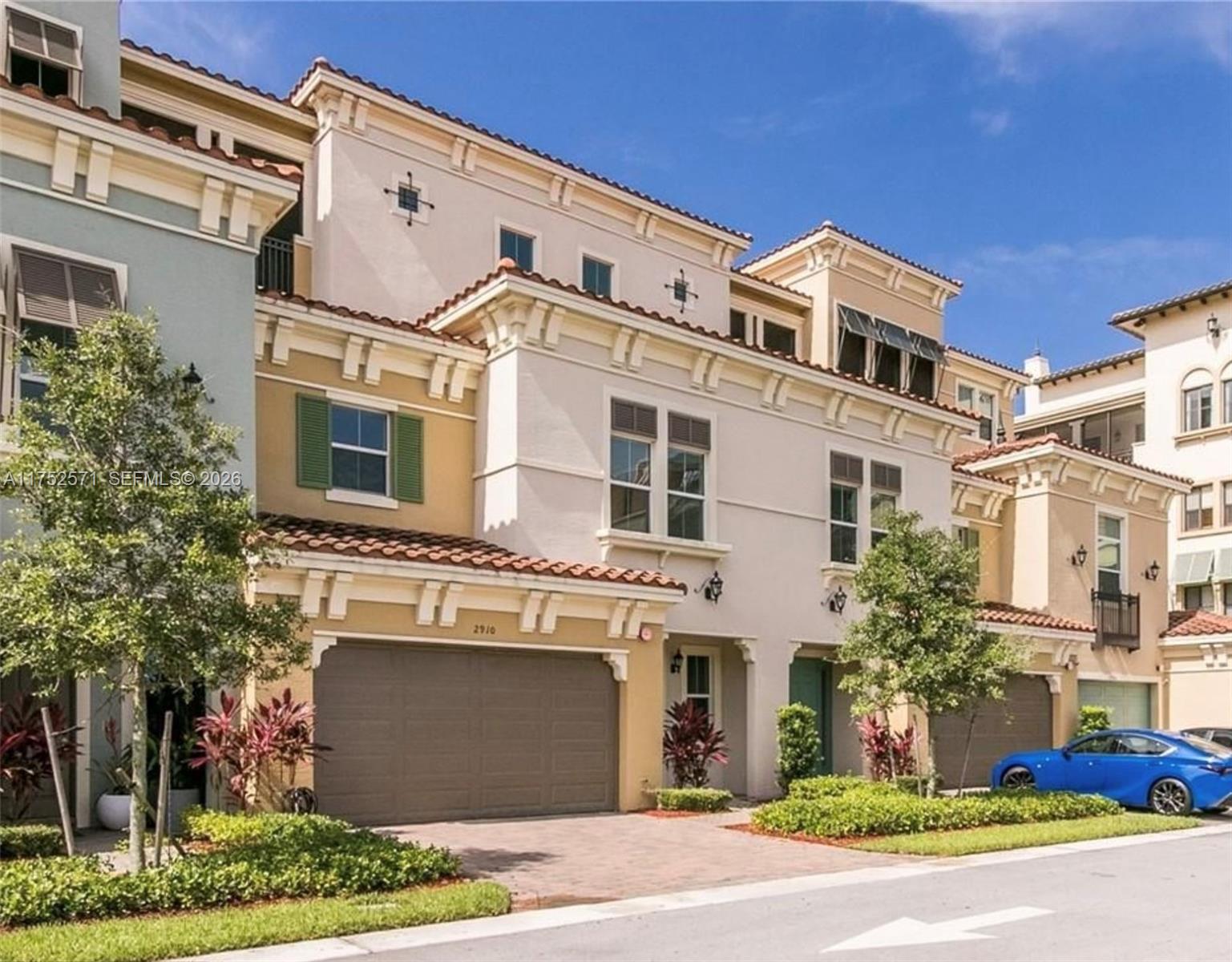 Exterior view of a multi-story Mediterranean-style townhouse with a garage and paved driveway — 2910 NW 124th Way # 2910, Sunrise FL 33323, SUNRISE, FL