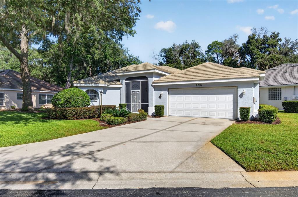 A single-story house with a two-car garage, a screened entryway, and a concrete driveway — 2791 GOLF LAKE DRIVE UNIT 55, PLANT CITY, FL