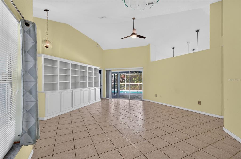 A living room with tile floors, a built-in white bookshelf, and sliding doors to a pool — 2791 GOLF LAKE DRIVE UNIT 55, PLANT CITY, FL