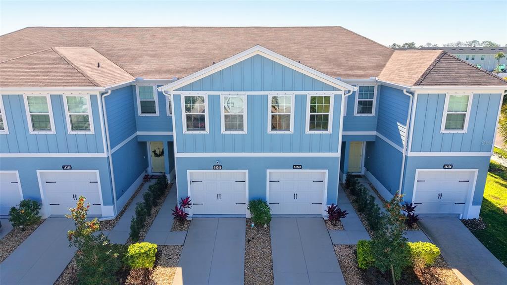 An aerial view of a blue multi-unit townhouse building with four garage doors and driveways — 14244 CRIMSON AVENUE, BRADENTON, FL