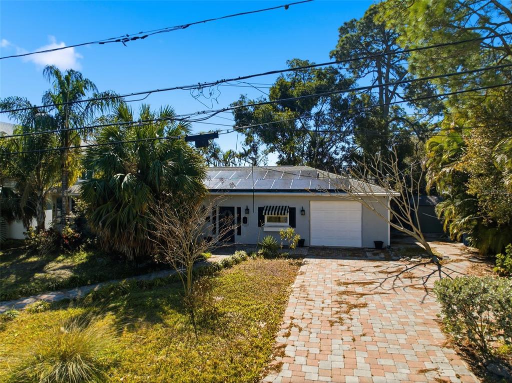 A single-story house with a paved driveway, solar panels, and mature landscaping — 208 48TH AVENUE N, ST PETERSBURG, FL