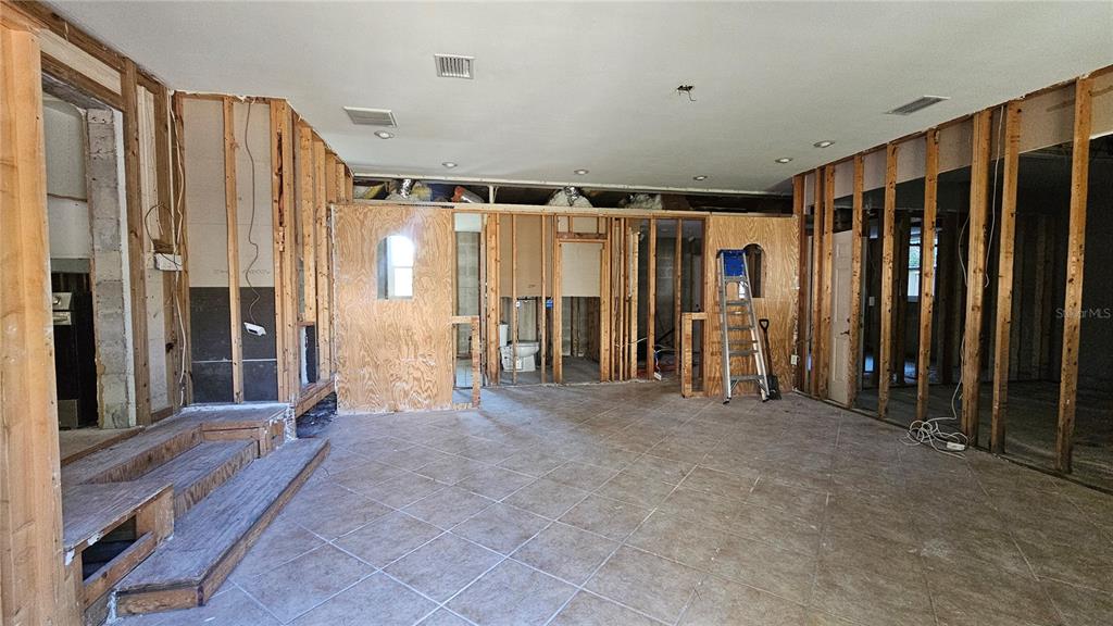 An interior room under construction features exposed wall studs, tiled flooring, and a wooden platform — 208 48TH AVENUE N, ST PETERSBURG, FL
