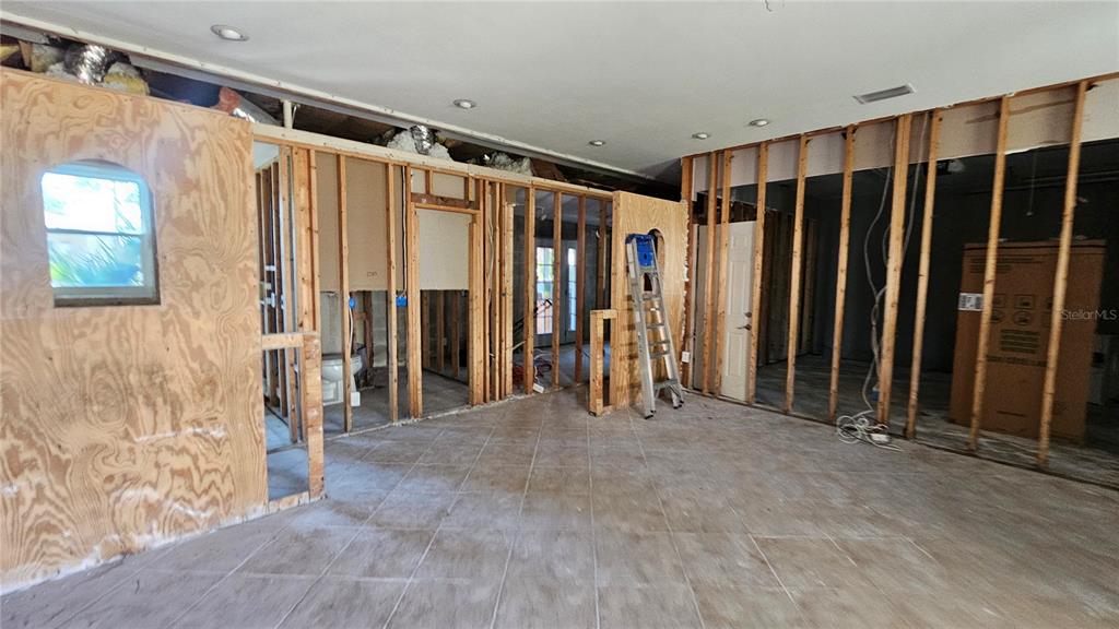 An interior room under construction features exposed wall studs, plywood panels, and tiled flooring — 208 48TH AVENUE N, ST PETERSBURG, FL