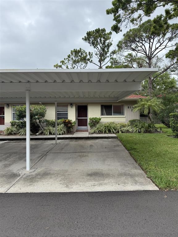 A covered carport sits in front of a single-story building with a tan exterior — 2460 NORTHSIDE DRIVE UNIT 206, CLEARWATER, FL