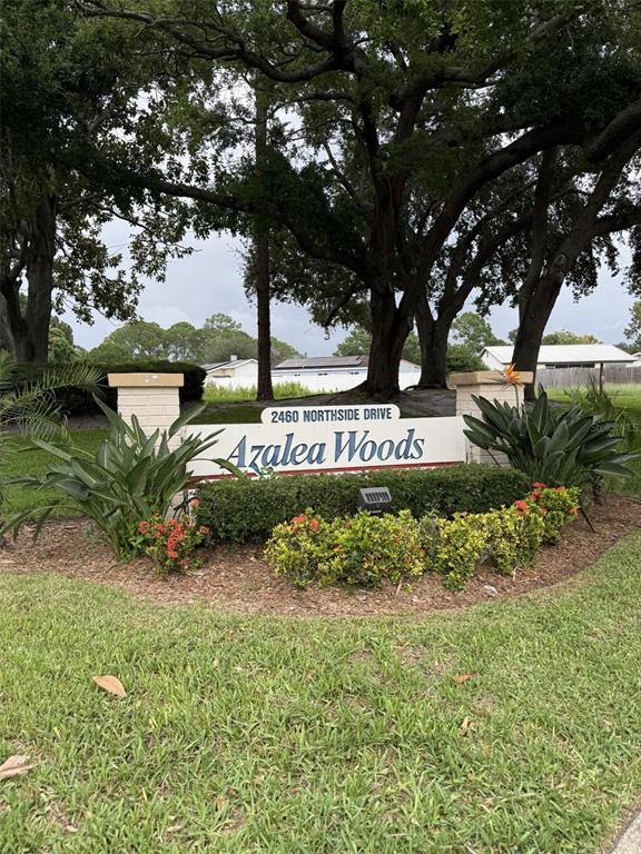 A community entrance sign for Azalea Woods sits in a landscaped garden bed under trees — 2460 NORTHSIDE DRIVE UNIT 206, CLEARWATER, FL