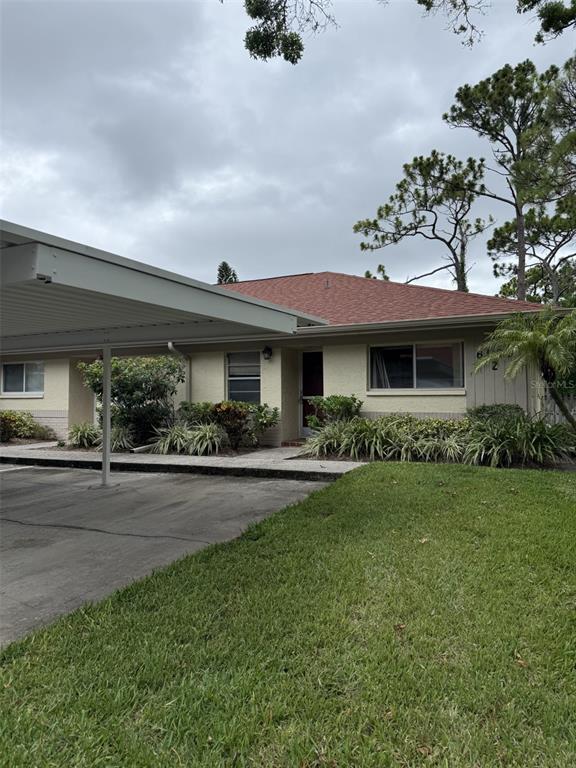A single-story house with a carport, tan stucco exterior, and a red shingled roof — 2460 NORTHSIDE DRIVE UNIT 206, CLEARWATER, FL