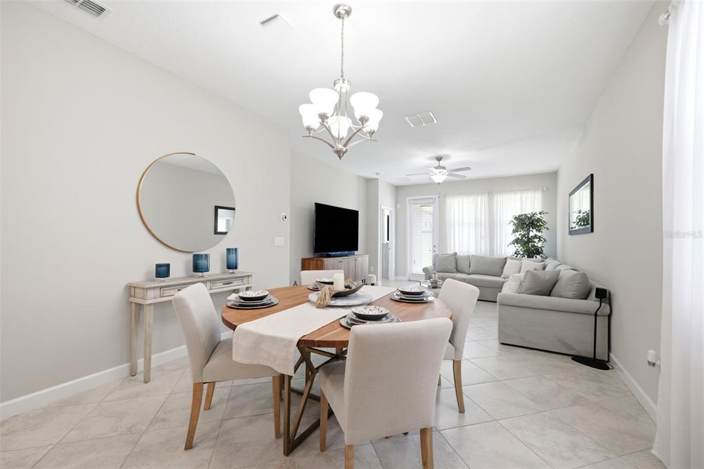 A dining area with a round wooden table and chandelier opens into a living room — 9927 IVORY DRIVE, RUSKIN, FL