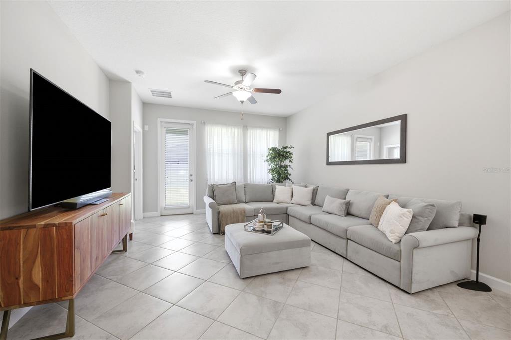 A living room features a large grey sectional sofa, a matching ottoman, and a television console — 9927 IVORY DRIVE, RUSKIN, FL