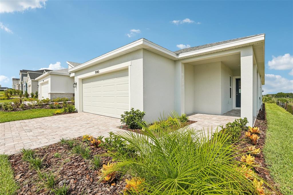 A single-story house with a white stucco exterior, a two-car garage, and a paved driveway — 1940 DIAMOND HEAD CIRCLE, HAINES CITY, FL