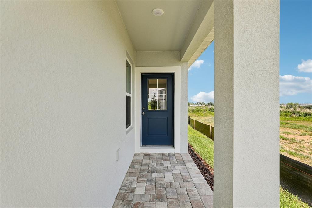A covered entryway features a blue door with a window and stone paver flooring — 1940 DIAMOND HEAD CIRCLE, HAINES CITY, FL