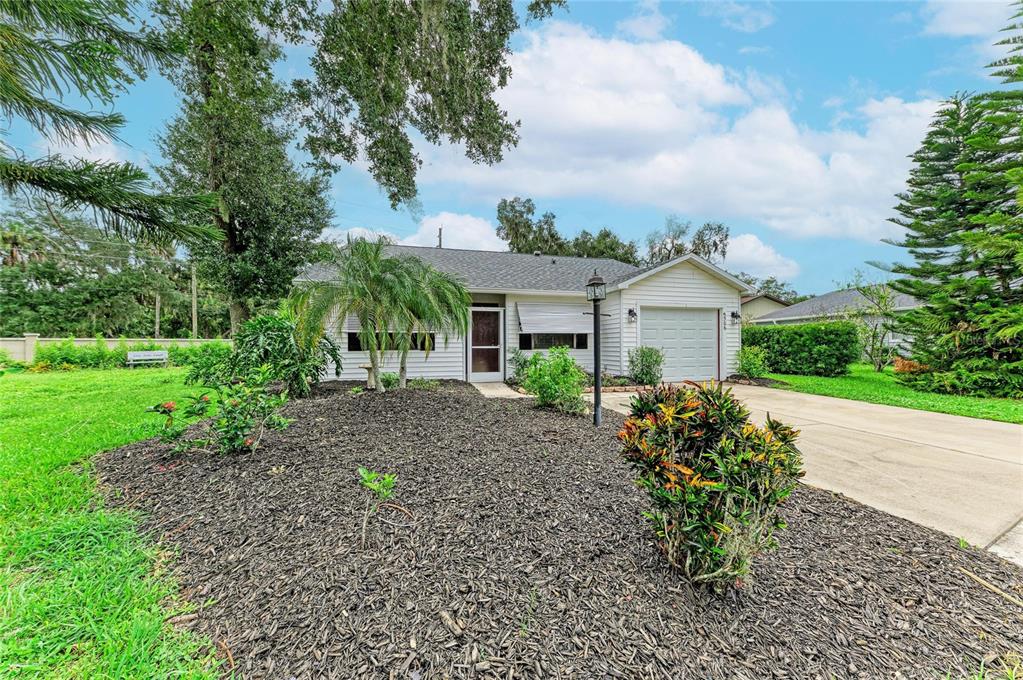 A single-story house with white siding, a front-facing garage, and a landscaped front yard — 5506 82ND AVENUE DRIVE E, PALMETTO, FL
