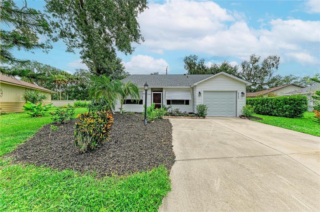 A single-story house with white siding, a concrete driveway, and a landscaped front yard — 5506 82ND AVENUE DRIVE E, PALMETTO, FL