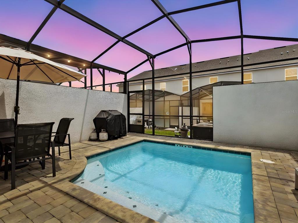 A small swimming pool sits on a paved patio inside a screened-in outdoor enclosure — 1632 TROPICAL PALMS CIRCLE, KISSIMMEE, FL