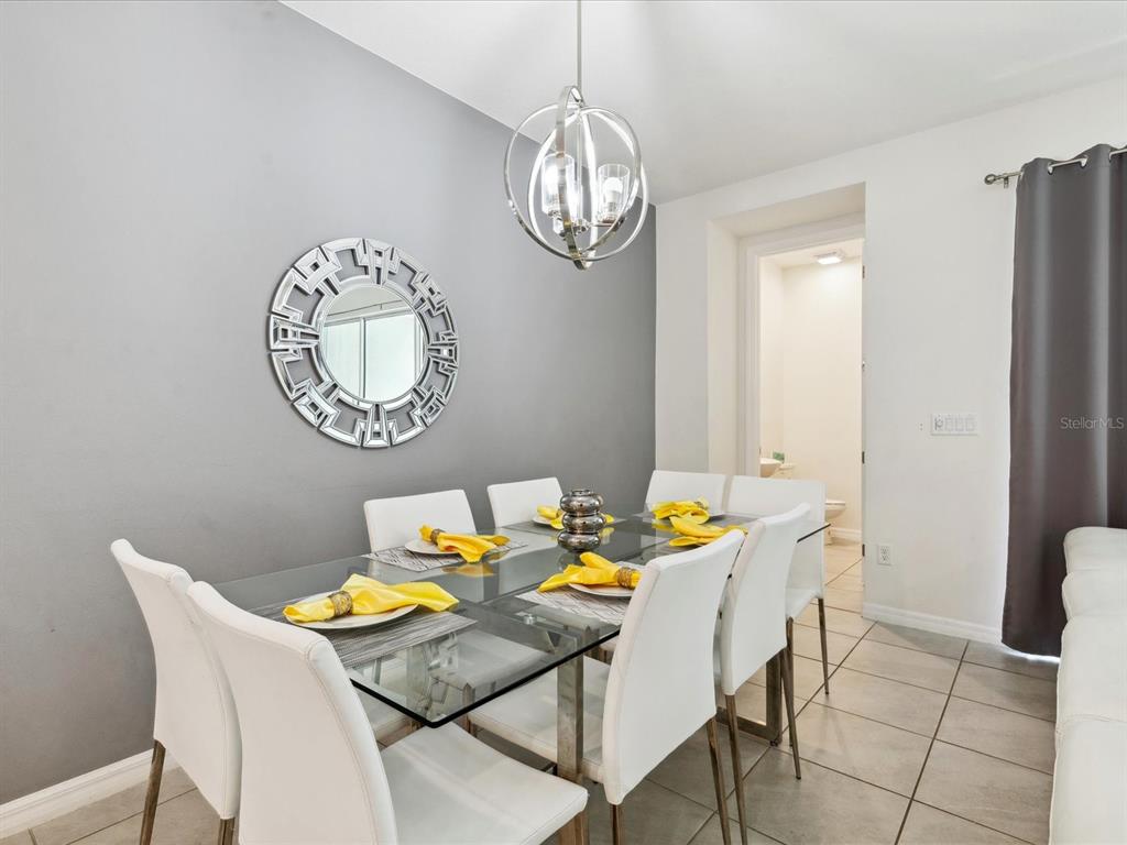 A dining room features a glass table, white chairs, a round mirror, and a chandelier — 1632 TROPICAL PALMS CIRCLE, KISSIMMEE, FL
