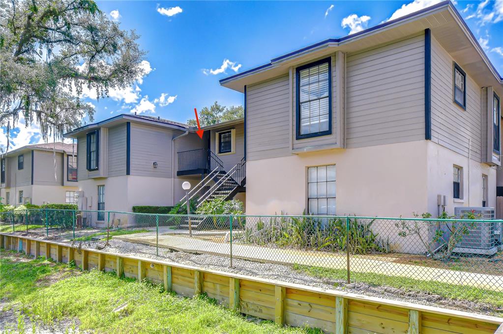 Exterior view of a two-story apartment building with an outdoor staircase and a chain-link fence — 4008 ASHFORD GREEN PLACE UNIT F204, TAMPA, FL