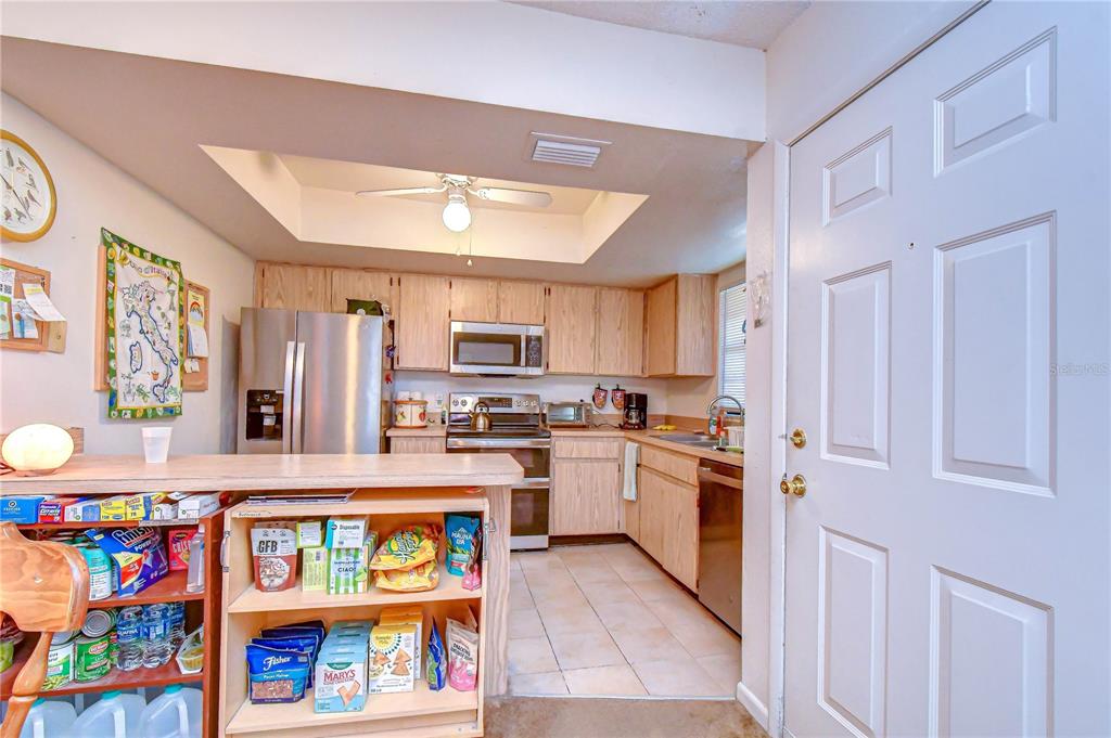 A kitchen with light wood cabinets, stainless steel appliances, and a breakfast bar island — 4008 ASHFORD GREEN PLACE UNIT F204, TAMPA, FL