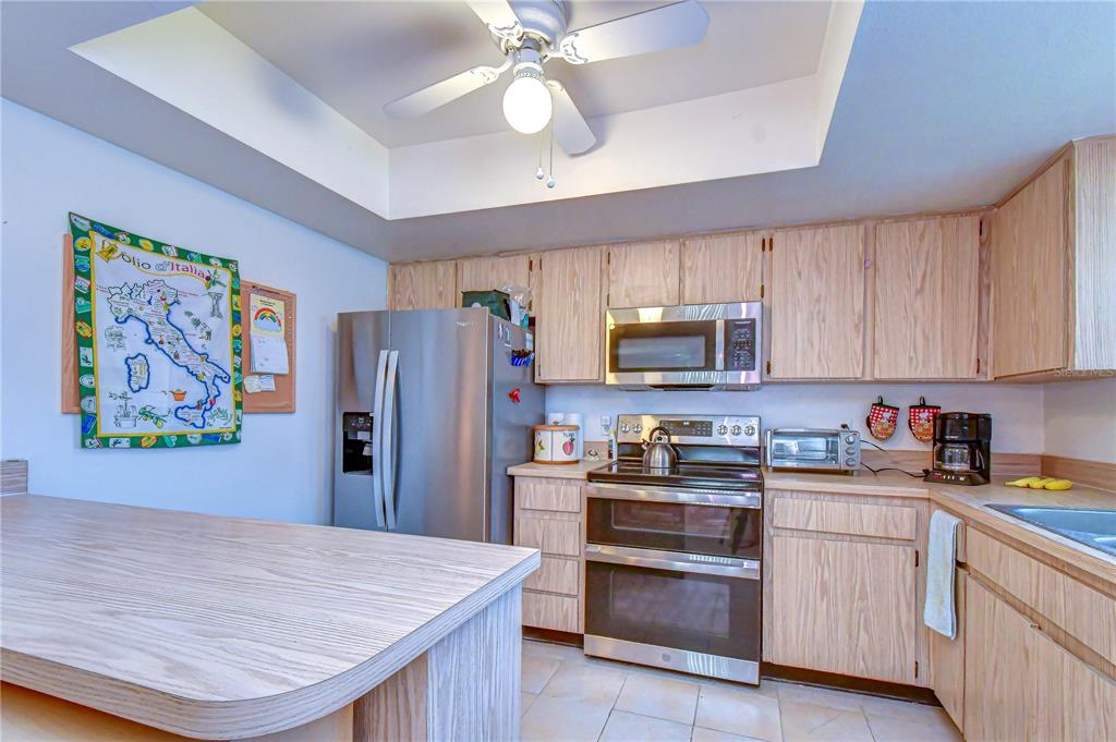 A kitchen features light wood cabinets, stainless steel appliances, and a central island — 4008 ASHFORD GREEN PLACE UNIT F204, TAMPA, FL