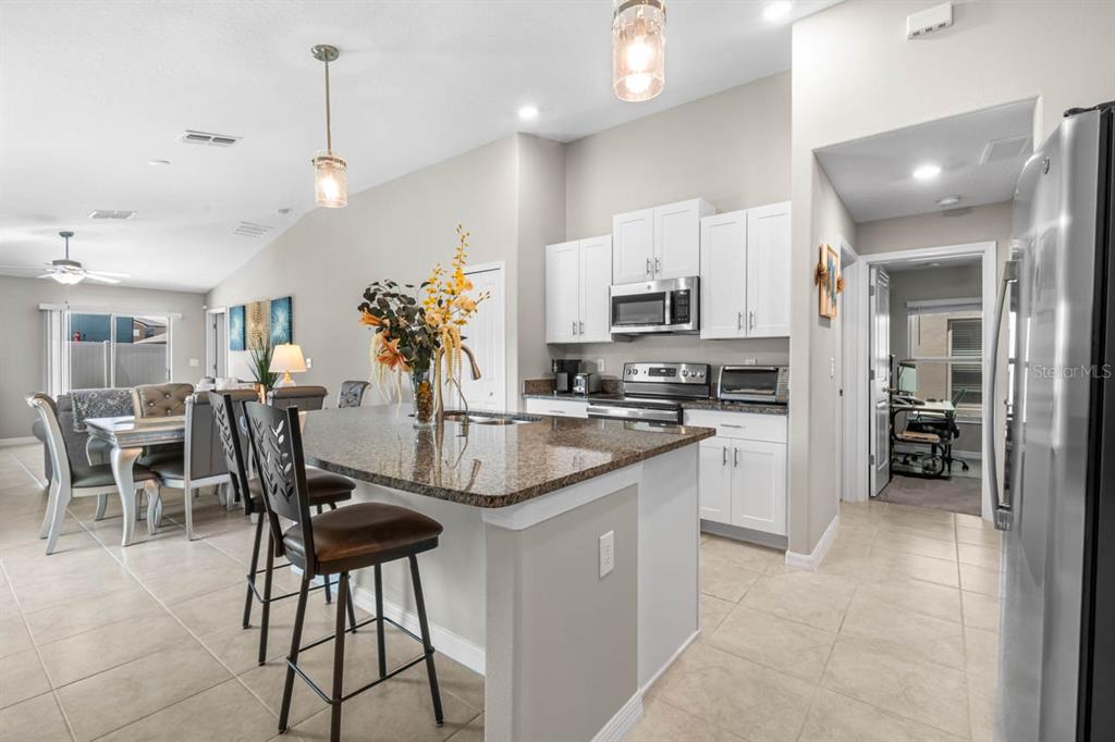 A kitchen with white cabinets, granite countertops, and an island with bar stools — 15477 MILLER CREEK DRIVE, SUN CITY CENTER, FL