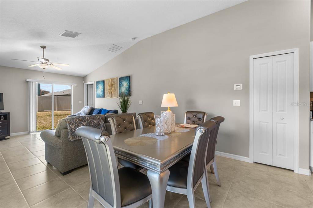 A dining area with a metallic table and chairs sits adjacent to a living room — 15477 MILLER CREEK DRIVE, SUN CITY CENTER, FL